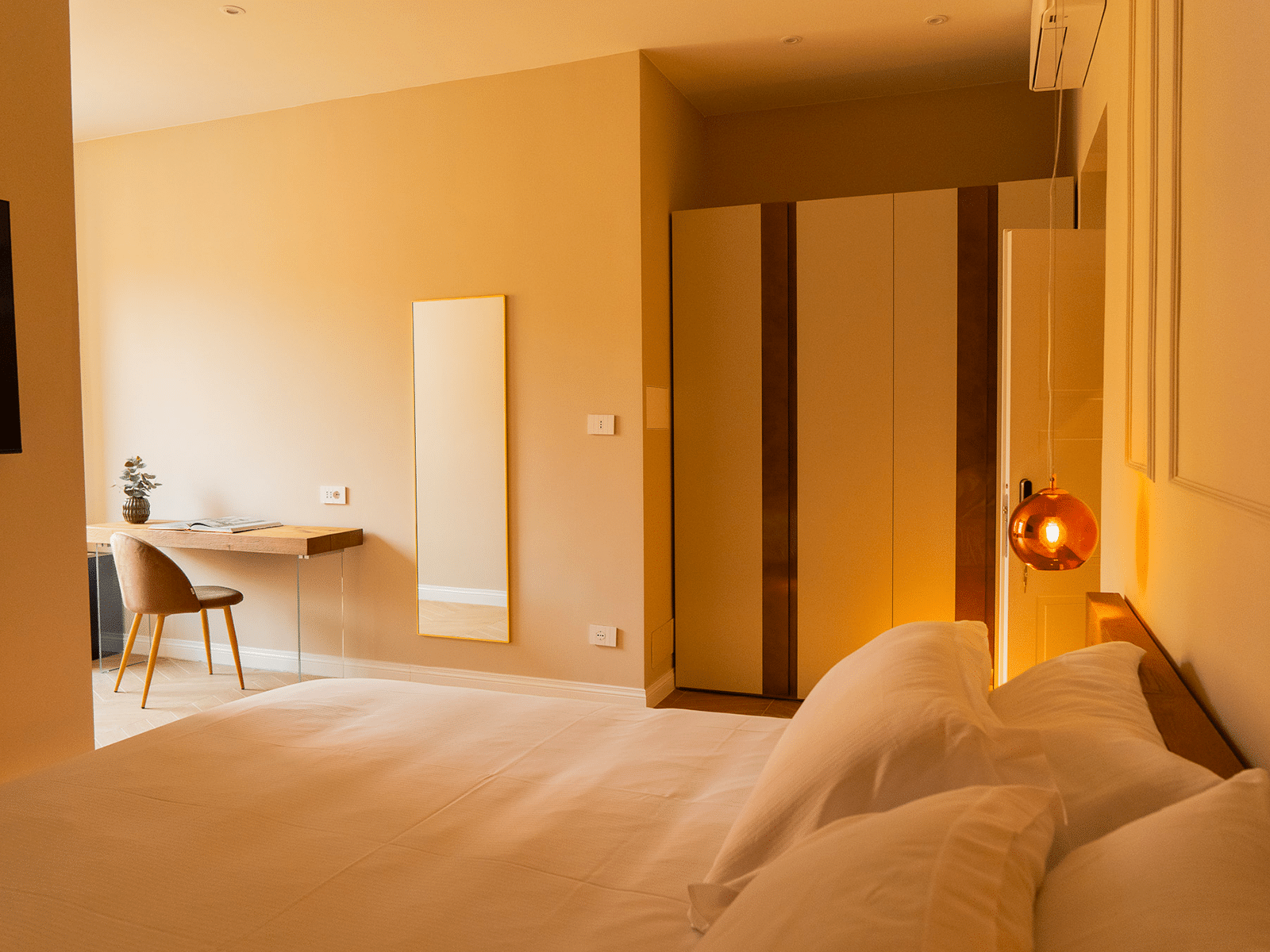 Elegancia y Comodidad en GV Suite Cámara elegante con cama matrimonial, escritorio y espejo.