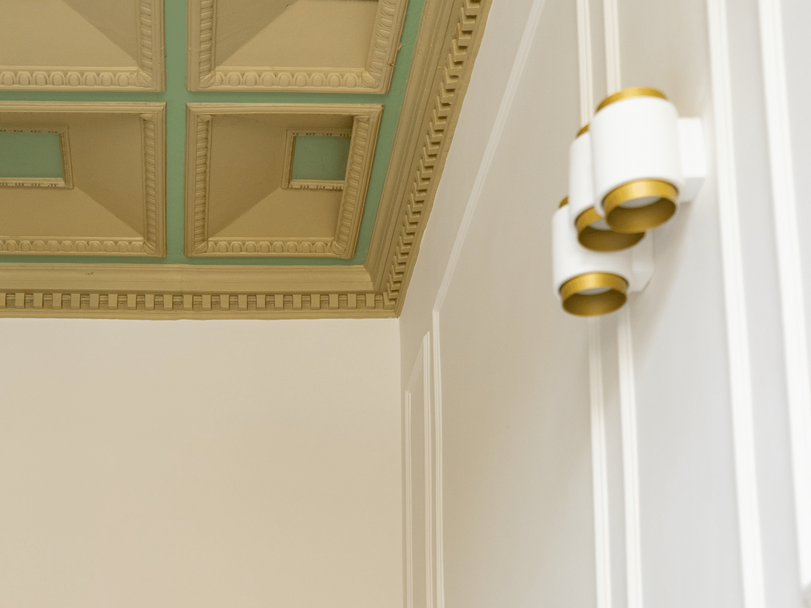 Elegancia y Refinamiento en GV Suite Detalle del techo decorado con molduras clásicas e iluminación moderna.