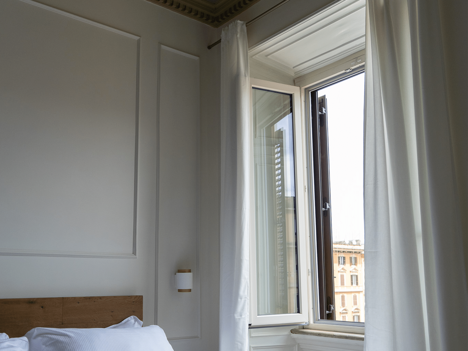 Elegancia Discreta en el Corazón de Roma Cámara luminosa con ventana abierta y vista al centro de Roma.