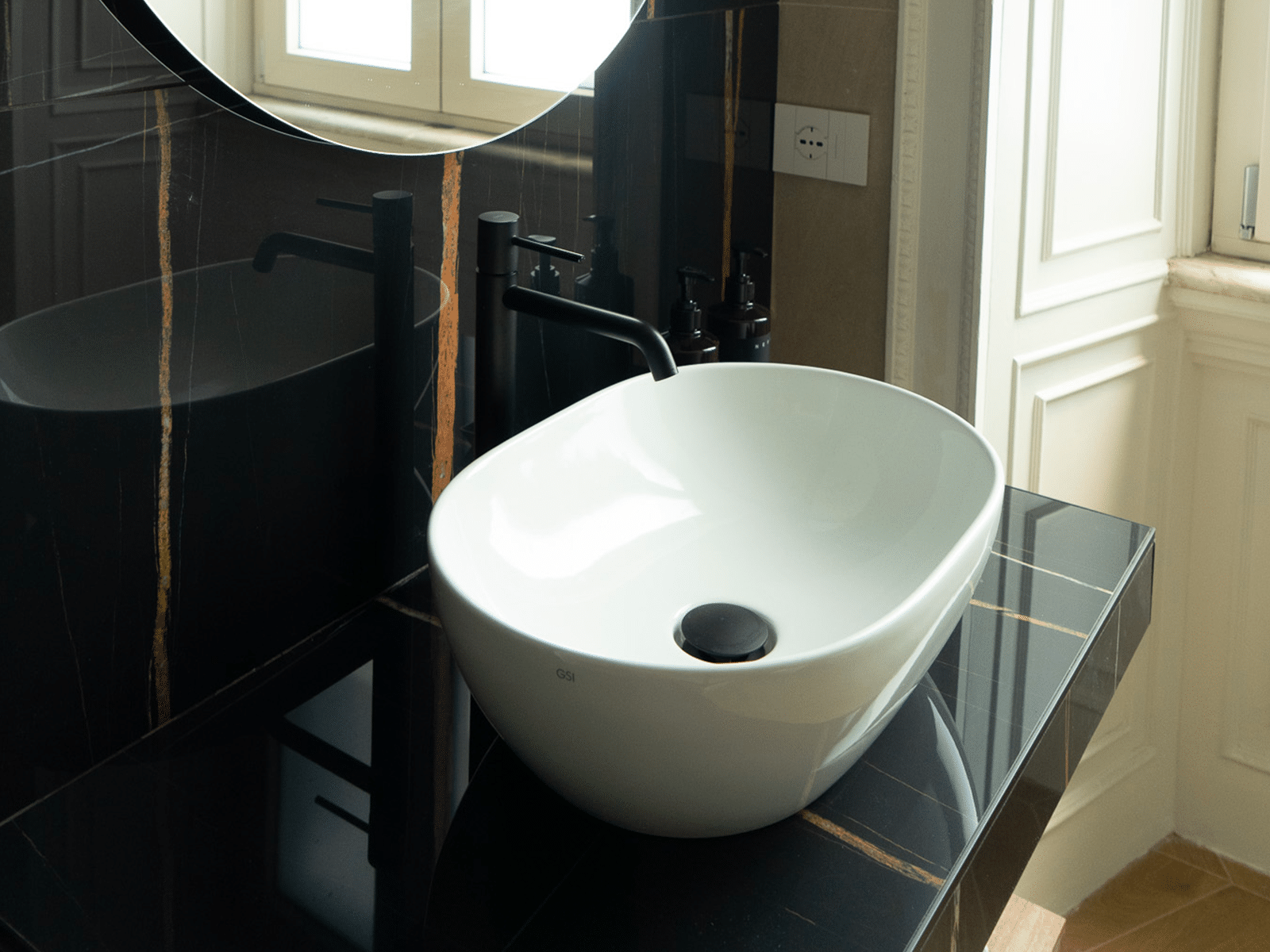 Salle de bain luxueuse dans une suite élégante. Élégant lavabo blanc sur plan noir dans une salle de bain design.