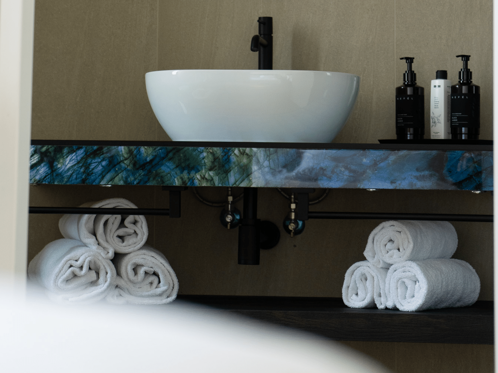 Élégance Subtile dans une Salle de Bain Moderne Lavabo moderne avec plan en marbre artistique, serviettes roulées et articles de toilette design dans la Family Deluxe.