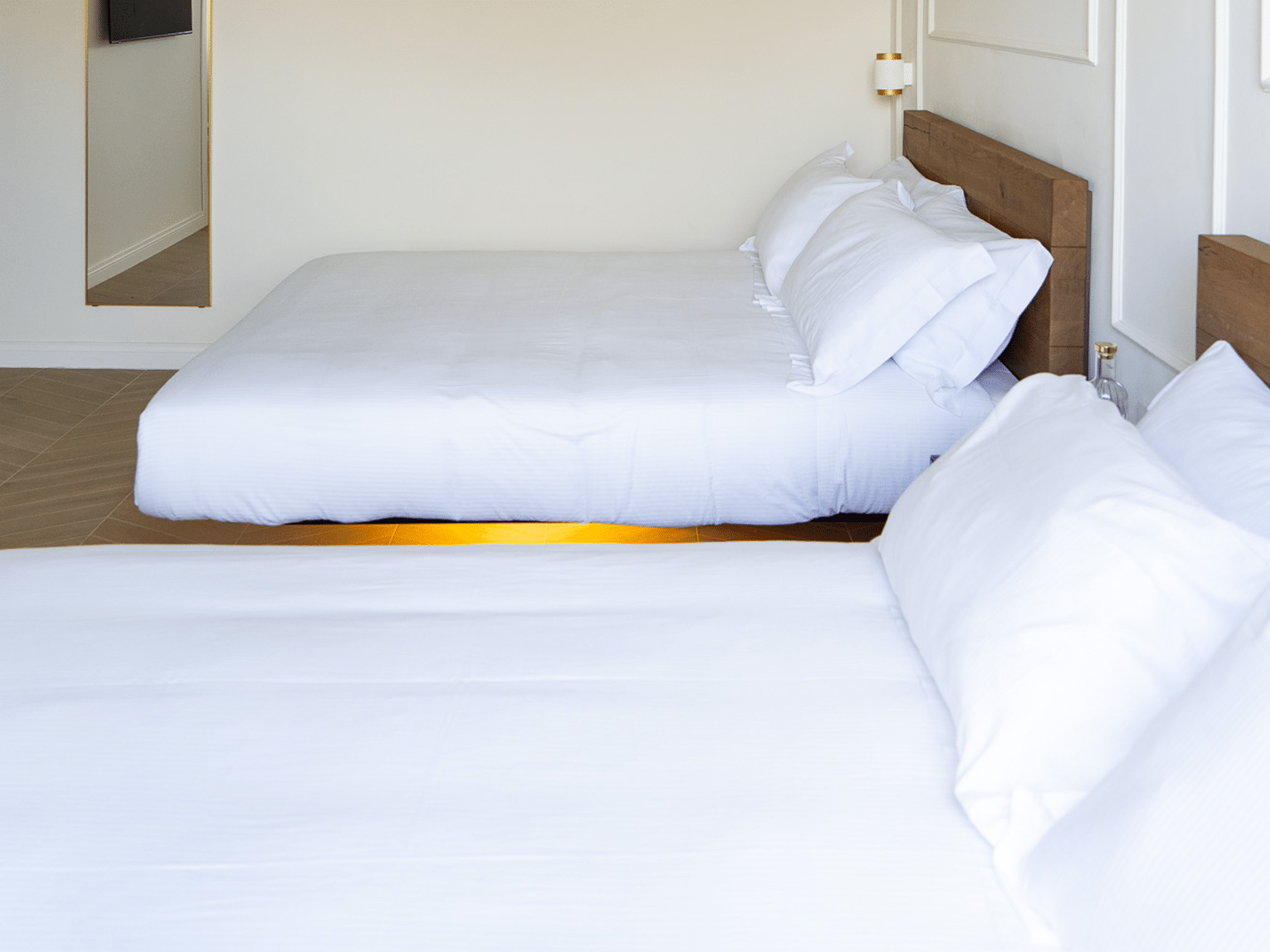 Élégance et Confort dans les Suites Rome Deux lits queen size avec linge blanc, mobilier de luxe.