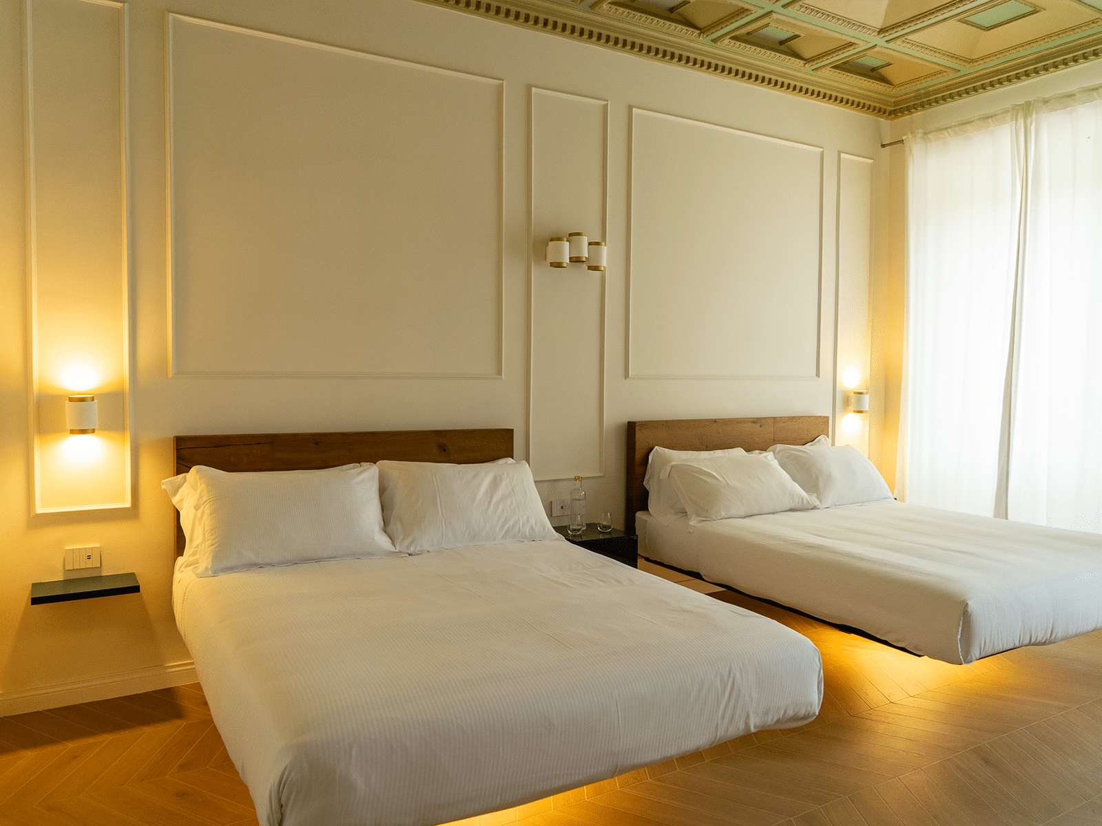 Family Deluxe – Design et Confort Unis Chambre Familiale Deluxe avec des détails de design moderne et des lits disposés pour accueillir des familles à Rome.
