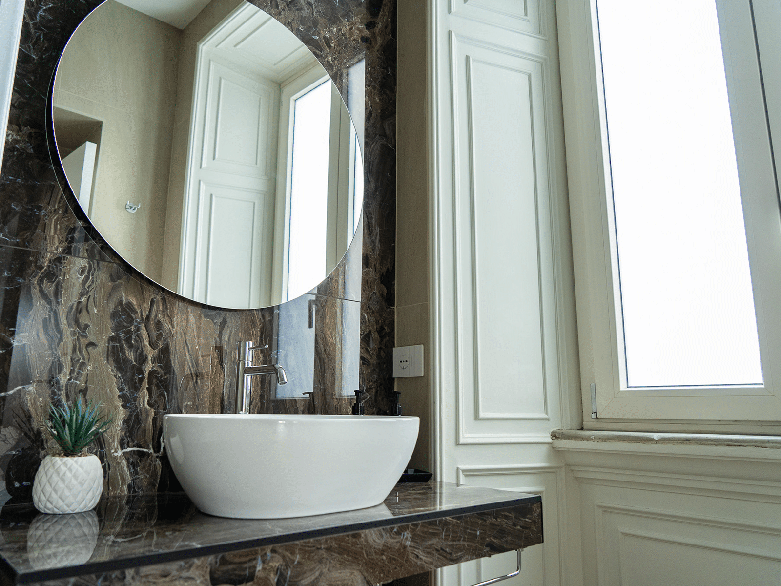 Élégance Raffinée dans Suite Luxueuse Salle de bain élégante avec lavabo moderne et miroir circulaire, entourée de marbre design.