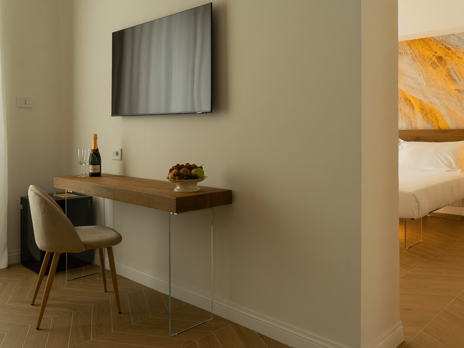 Élégance Moderne dans la Suite GV Intérieur d'une suite élégante avec bureau en bois, chaise, télévision moderne et aperçu du lit.