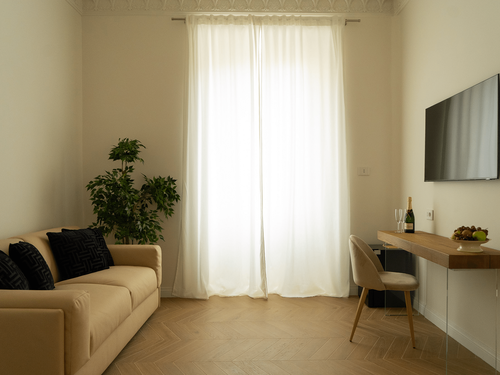 Élégance et Confort à GV Suite Salon élégant avec canapé beige, plante et bureau.