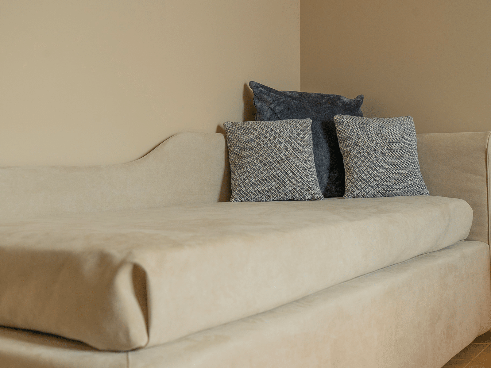 Divano imbottito beige con cuscini decorativi in una camera Deluxe di GV Suite Collection, pensato per momenti di relax